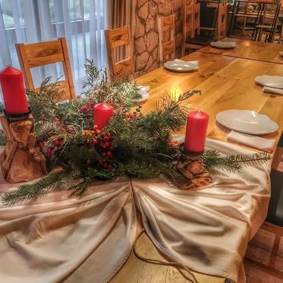 Nakryty drewniany stół w sali restauracyjnej ze świecami i zielonym stroikiem